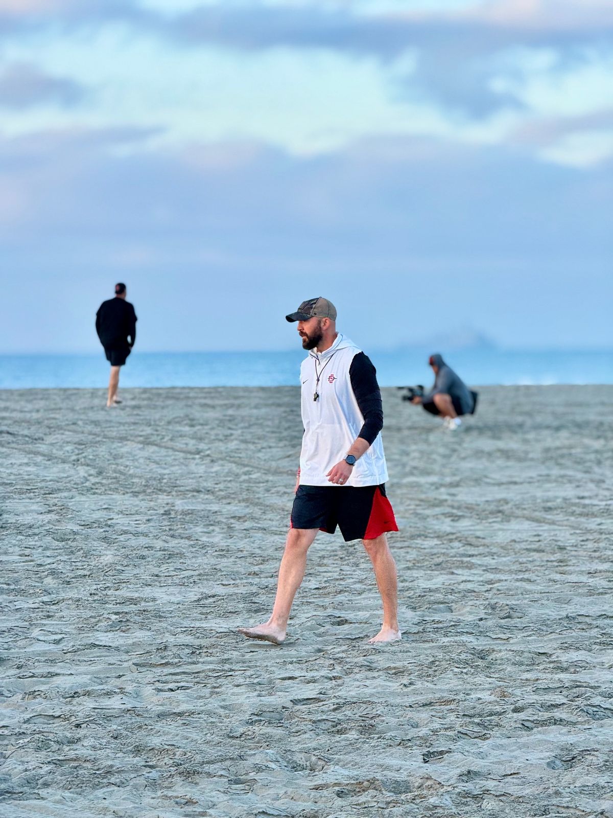 Sean Lewis stalks across the beach at Coronado Bay as his third Aztecs squad readies for a grueling workout. 
